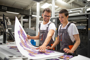 pressman talking to assitant about press sheet in a local print shop